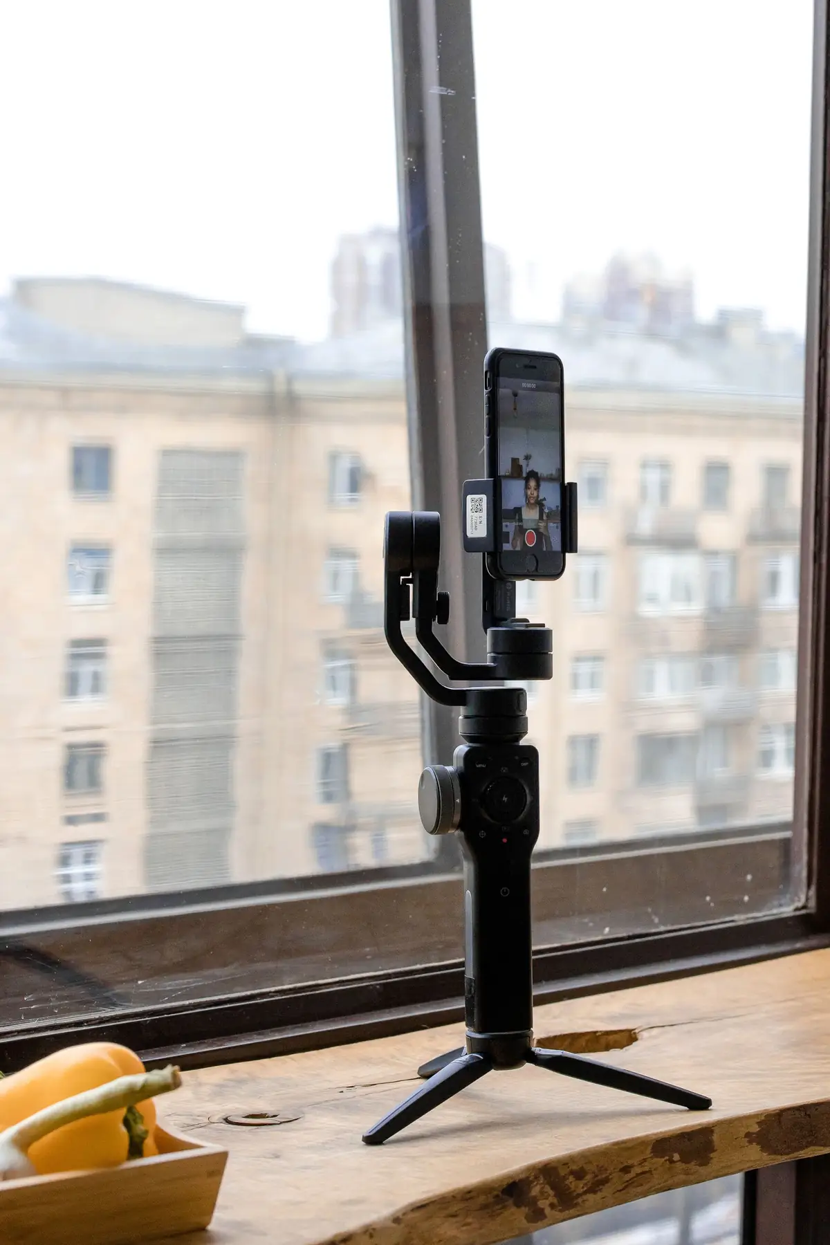 A smartphone on a tripod recording video by a window